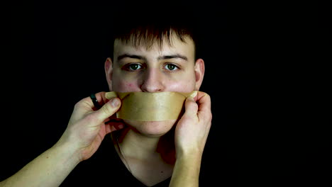 person placing tape over mouth of young man, slow motion