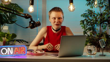 young woman broadcasting or podcasting in a home studio with 'on air' sign