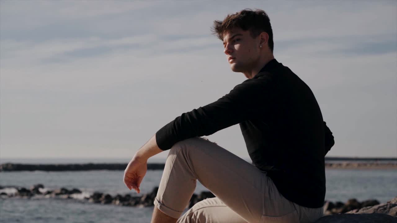 Drengen er på klipperne i havet om morgenen