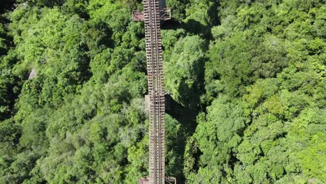 Bird's Eye View of high railroad track bridge crossing a valley with a lone hiker starting to cross it on a sunny day