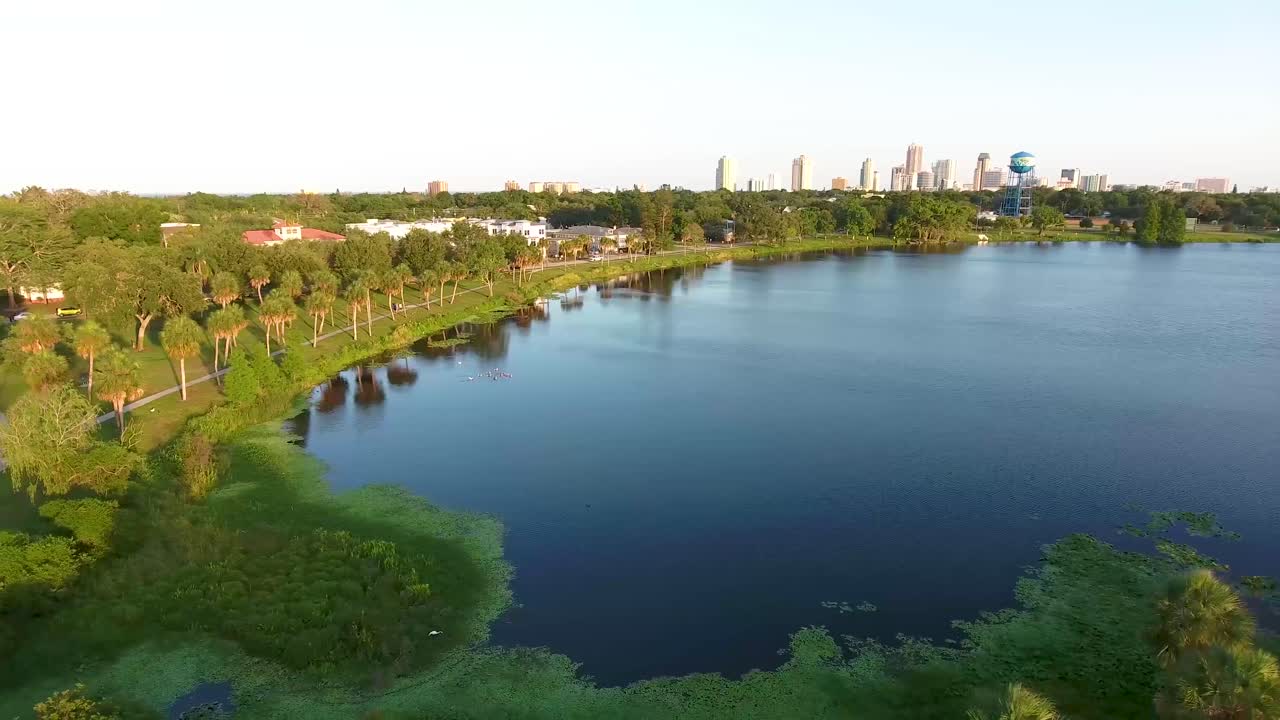 플로리다 주 세인트 피터스버그 시내를 향해 나무와 호수 위로 4k 공중 돌리 비디오