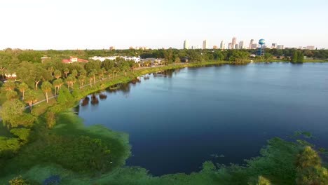 4K-Aerial-Dolly-Video-Over-Trees-and-Lake-Towards-Downtown-St-Petersburg,-FL