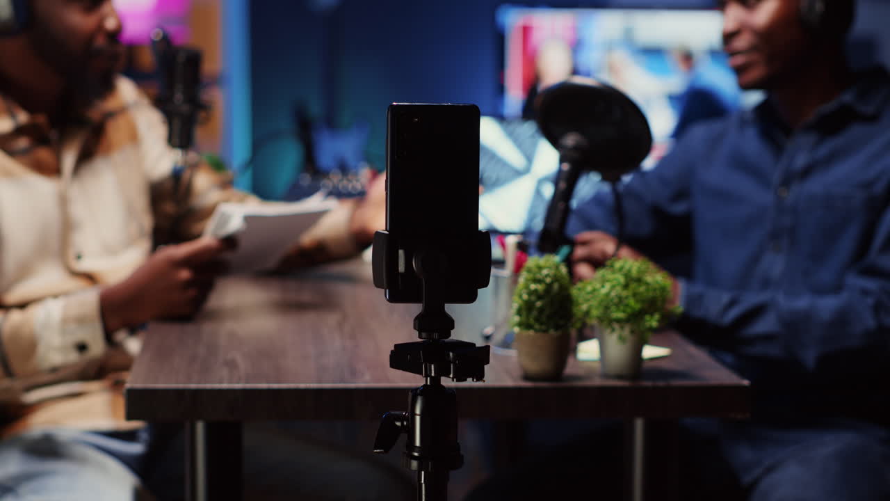 Podcast host using smartphone on tripod to record guest telling interesting story