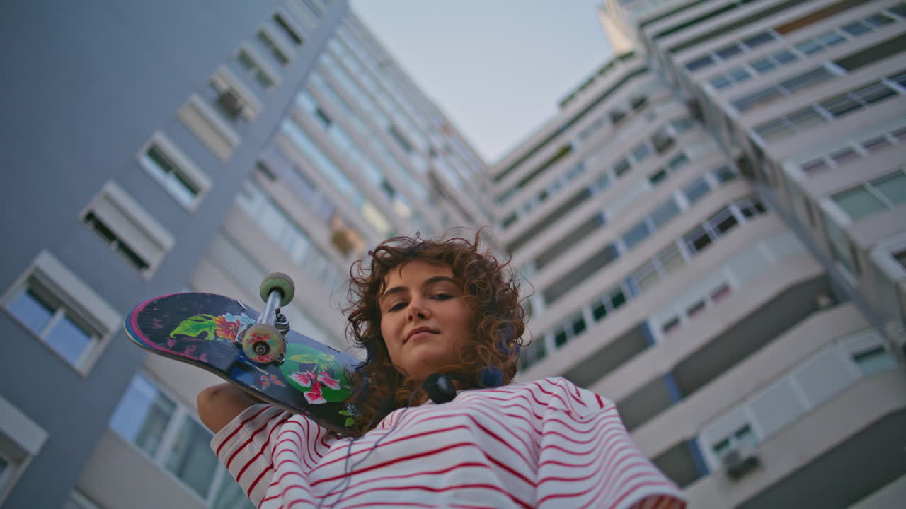 chica posando en una patineta mirando a la cámara en la calle de cerca. mujer con patineta