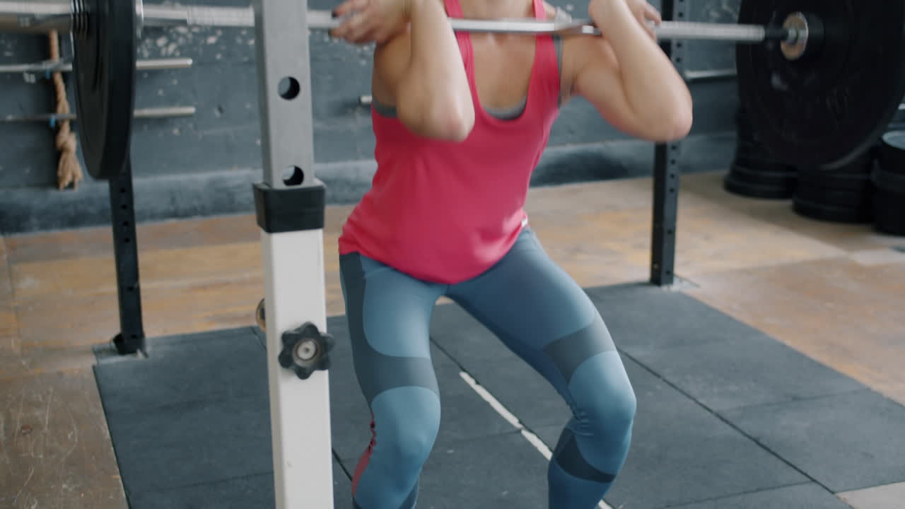 Donna che esegue squat posteriore con bilanciere in palestra