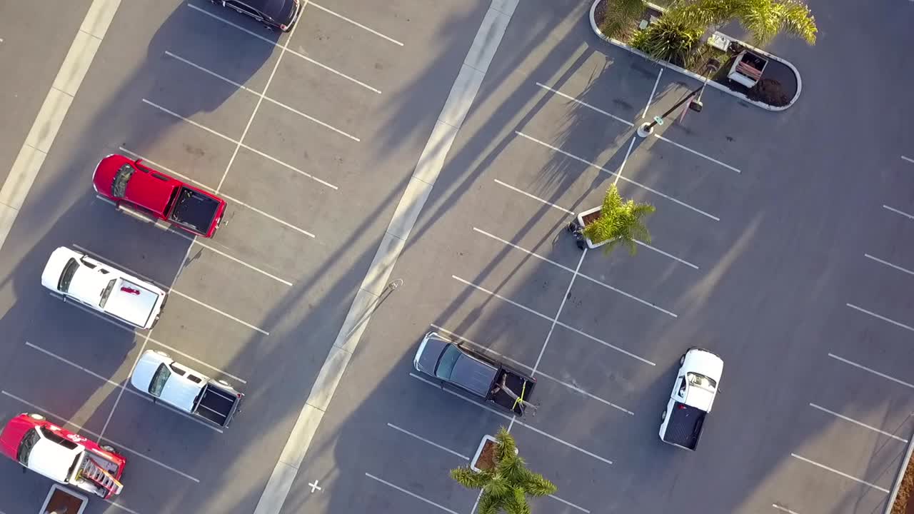 Zona de aparcamiento con coches y camionetas pick-up, coche blanco