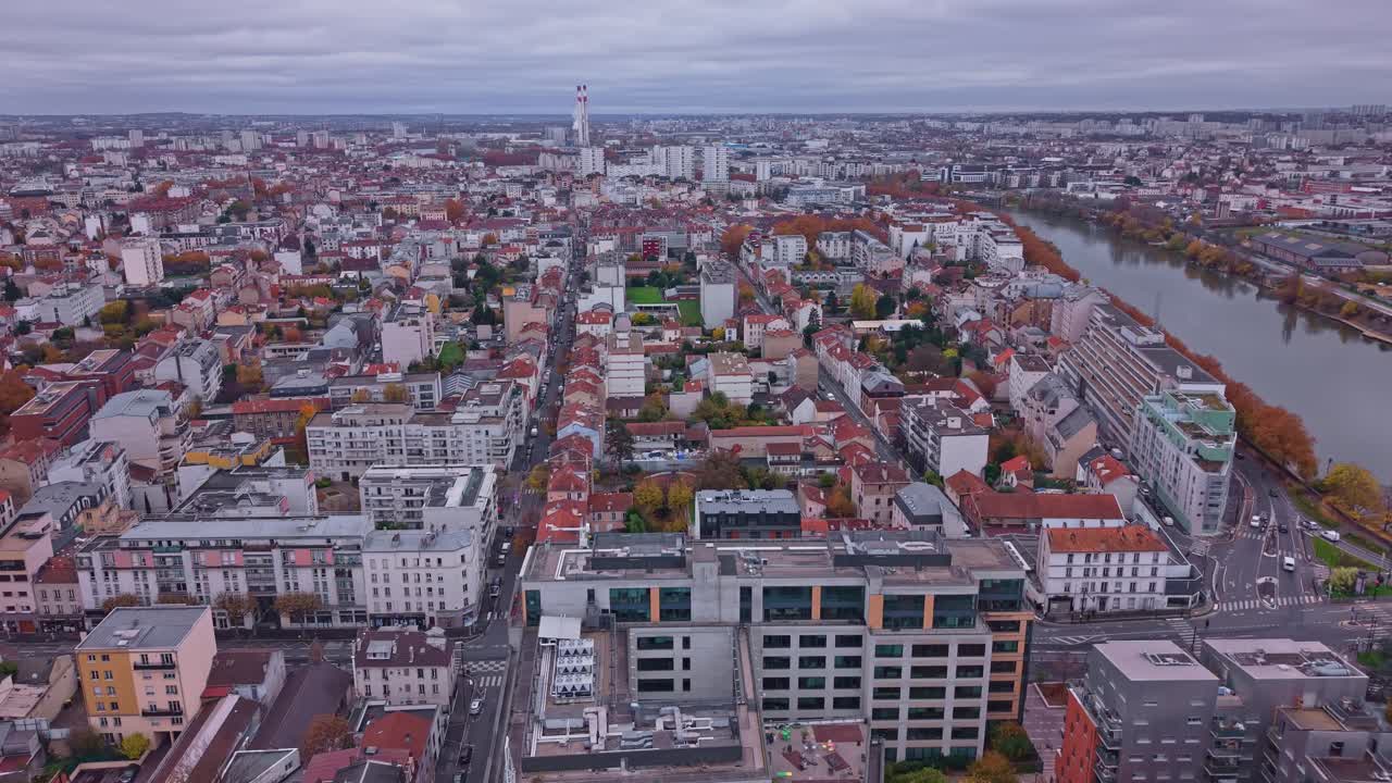 Drone advances over Alfortville rooftops with Seine River along the city edge