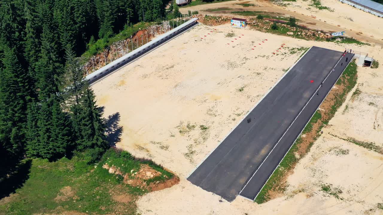 unrecognisable group of people skating on pavement near forest. Bosnia. Aerial view