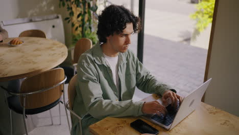 man working on laptop at a coffee shop