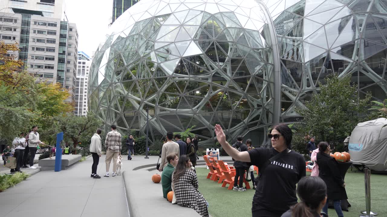 Video capturing families and visitors exploring the area near The Spheres at Amazon in Seattle. The scene features people relaxing, socializing, and enjoying outdoor activities by the glass domes.
