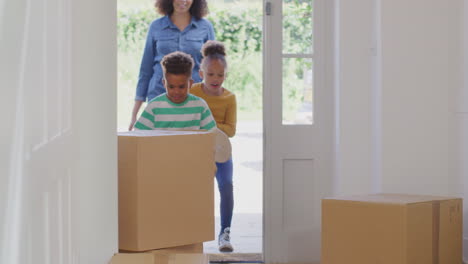 niños emocionados ayudando a la madre a llevar cajas a la nueva casa en el día de mudanza