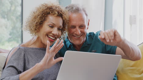 Pareja-De-Jubilados-Mayores-Sentados-En-Un-Sofá-En-Casa-Haciendo-Videollamadas-En-Una-Computadora-Portátil