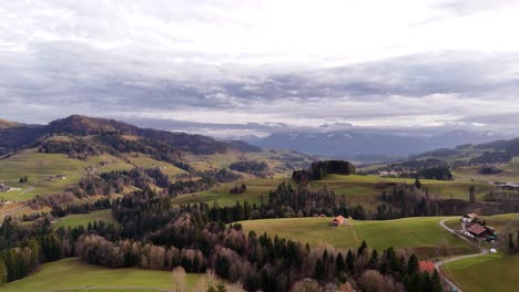 Vuelo-De-Drones-Sobre-Los-Paisajes-Montañosos-Del-Cantón-De-Zurich-En-Un-Día-Nublado-Con-Montañas-Al-Fondo