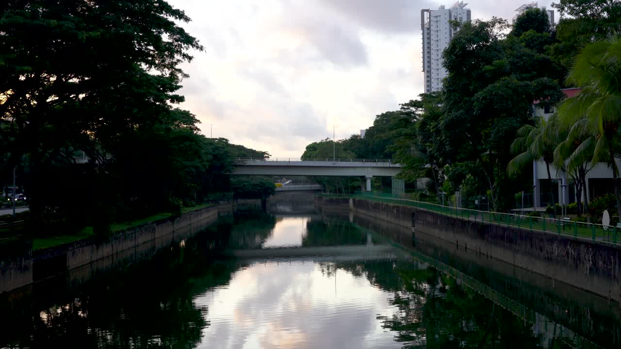 A scenic view of a bridge over a canal with trees and buildings in the background