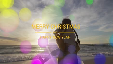 Animation-of-merry-christmas-text-over-biracial-mother-and-daughter-at-beach