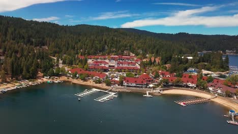 aerial reverse pull back shot tilting up to reveal charming mountain village on lake. 4k