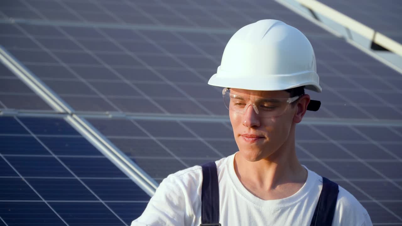 Young enginneer installing new sunny batteries. Worker in a uniform and hardhat installing photovoltaic panels on a solar farm. The future is today