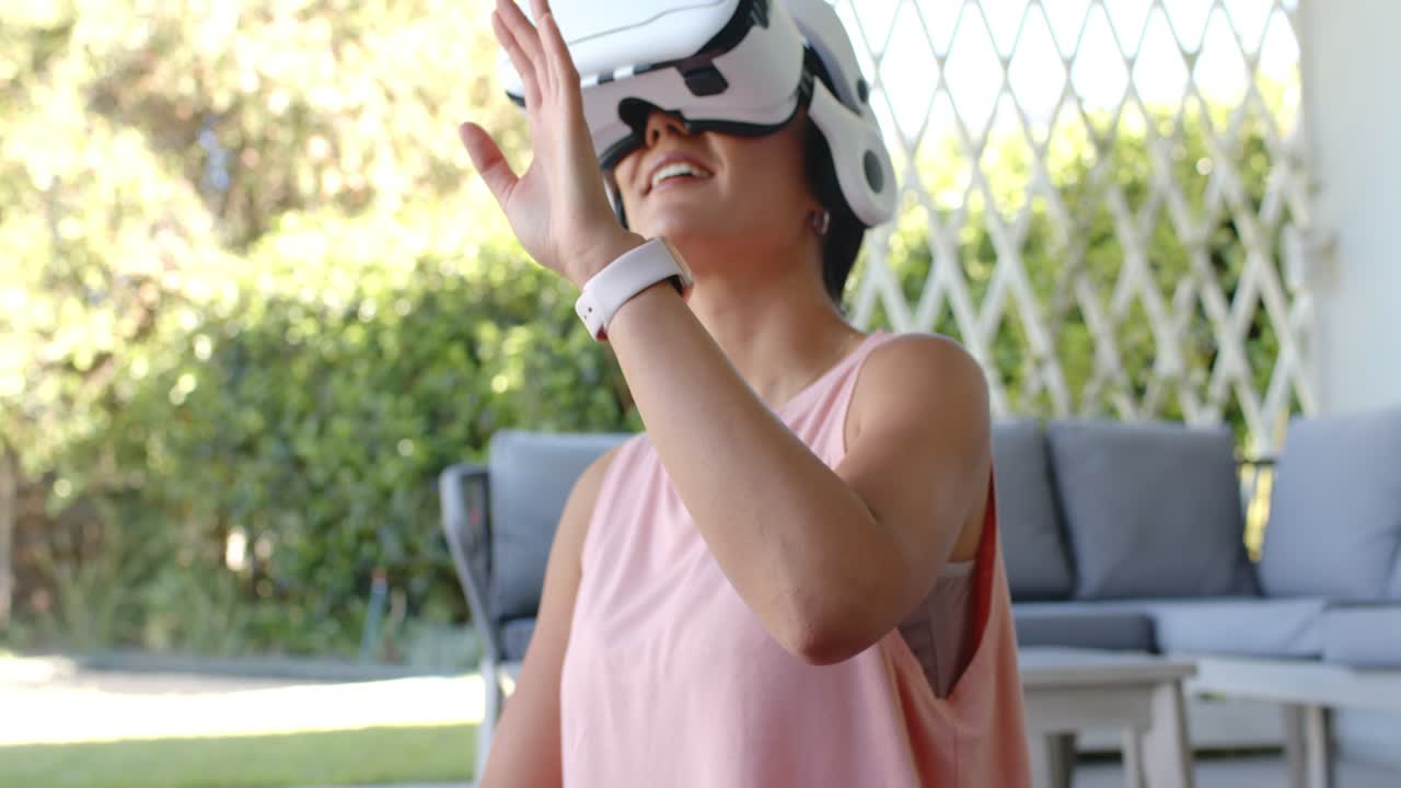 Adult woman on dark exercise mat, picking up white VR headset and reaching to explore menu