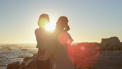 Happy-young-couple-interacting-with-each-other-on-rocky-shore-4k