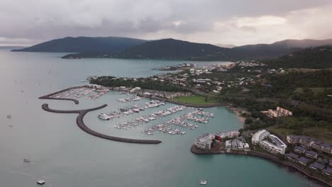 airlie playa bahía laguna mar de coral marina drone aéreo nubes de lluvia niebla amanecer corazón de la gran barrera de arrecifes whitsundays whitehaven muelle yates veleros edificios círculo a la izquierda