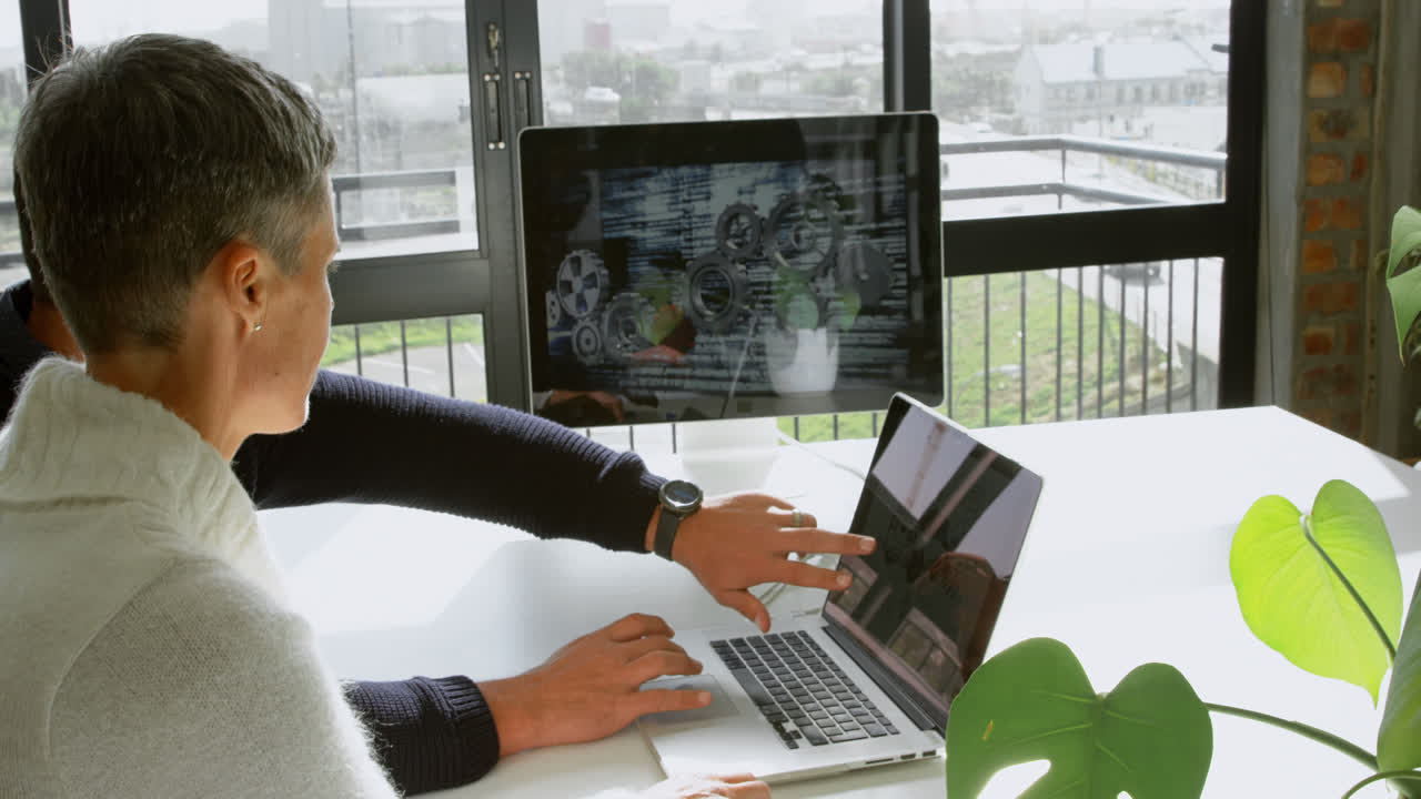 자동차 디자이너들이 4k 책상에서 노트북을 통해 논의하고 있습니다.