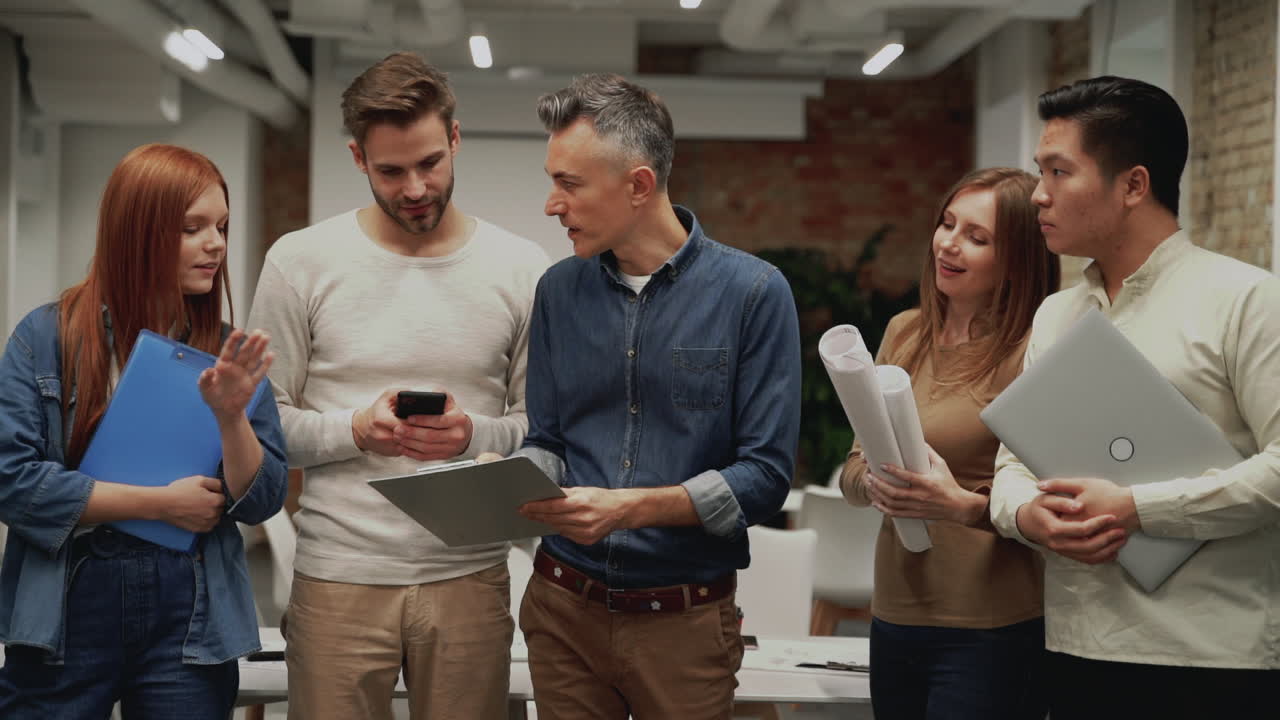 Multi ethnic work team standing. Meeting of young business men and women talking about a new project.