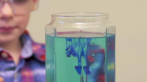 a little boy doing a science experiment by mixing colors