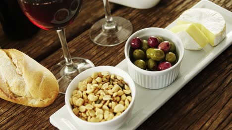 bowl of peanuts, olives and cheese served with red wine