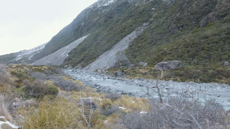 un lago glacial rocoso y corriendo entre montañas nevadas en medio del invierno en nueva zelanda