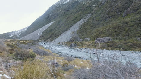 a running and rocky glacial lake running between snow capped mountains in the middle of winter in new zealand