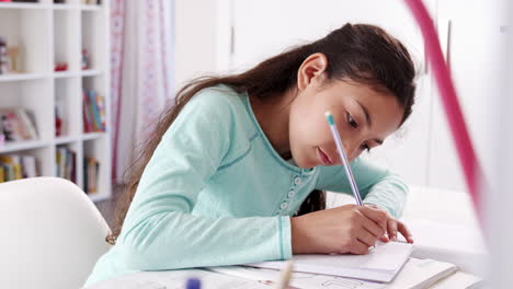 Una-Joven-Sentada-En-Un-Escritorio-En-El-Dormitorio-Haciendo-Los-Deberes