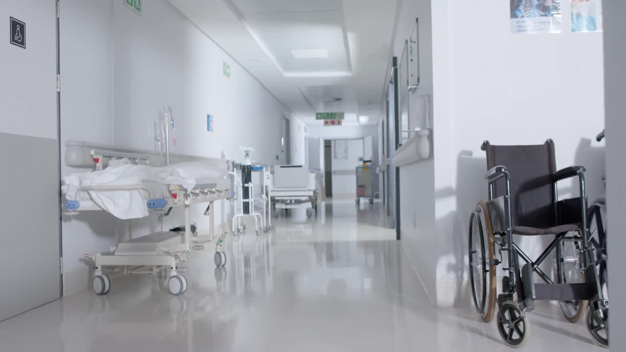 vista generale del corridoio dell'ospedale vuoto con sedie a rotelle e letti dei pazienti in slow motion