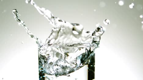 ice cube falling into glass of water