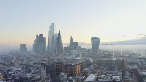 establishing aerial circling drone shot of london central business district foggy sunrise