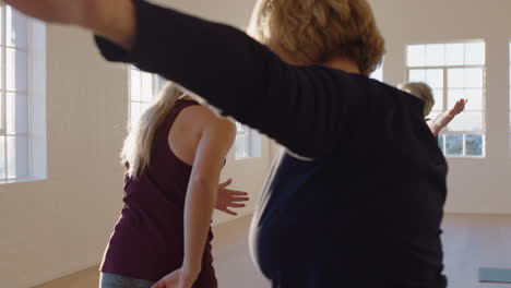 yoga class instructor teaching mature women practicing warrior pose enjoying healthy lifestyle in fitness studio at sunrise