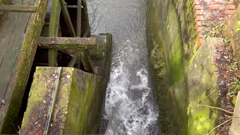 mossy water wheel and flowing waterfall crashing into small stream