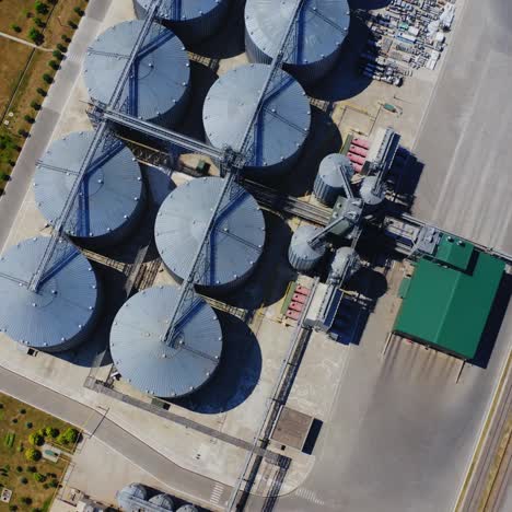 grain elevator. top view of steel containers for agriculture products on field. warehouse granary aluminum containers. camera rising up slowly.