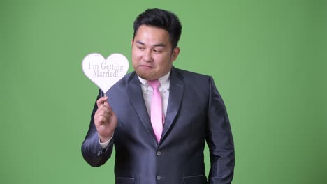 초록색 배경에 젊은 잘생긴 과체중 아시아 사업가