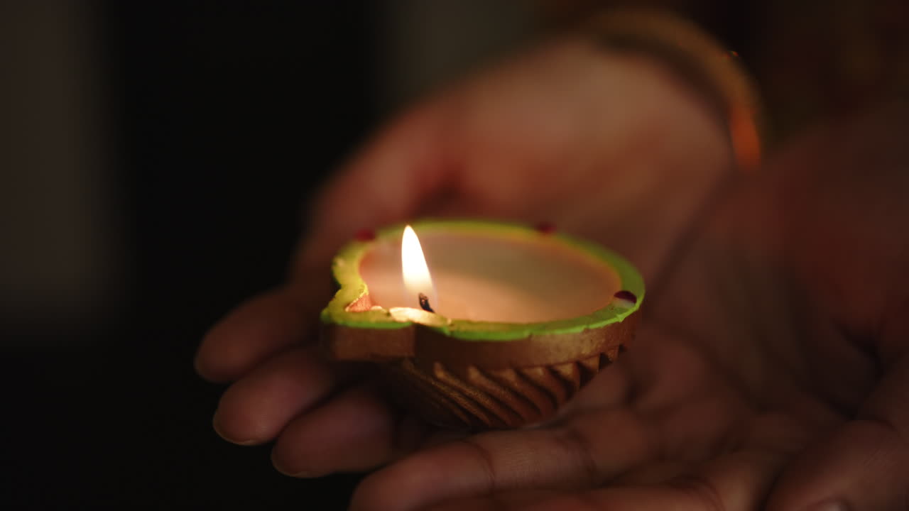 Holding lit clay lamp, hands celebrating traditional Indian festival Diwali