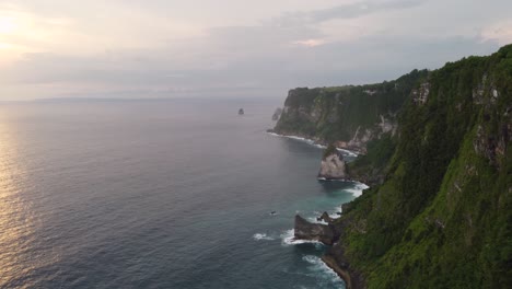 vista aérea del atardecer de la costa tropical de la isla de nusa penida altos acantilados y calas verdes escarpadas con vistas a las olas del océano índico que se estrellan contra las rocas en forma de diamante, indonesia