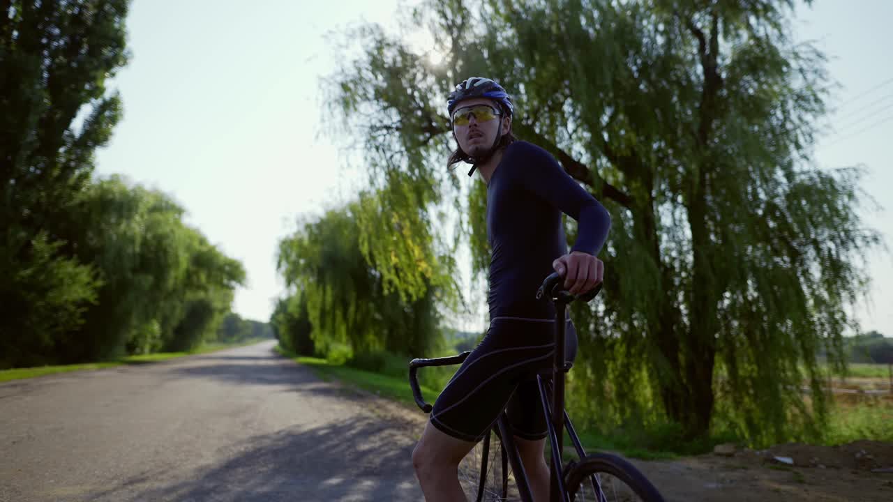 Portræt af cyklist på den tomme vej, der kigger sig omkring.