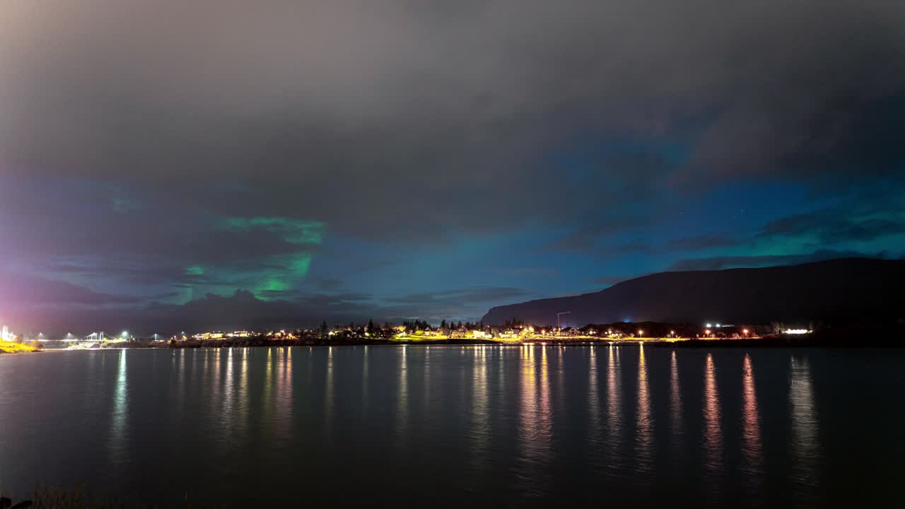 timelapse del cielo nocturno nublado de la aurora boreal junto al lago en islandia - toma amplia