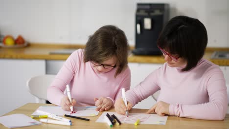 portrait of two girls draw with colorful pens at home