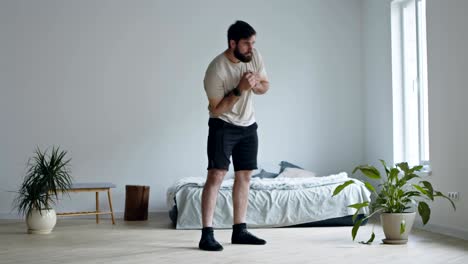 joven barbudo girando las caderas, haciendo ejercicio en el interior de la casa