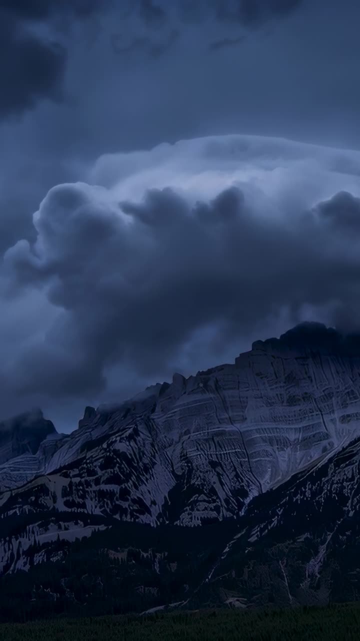 Vertical video: Bulging cloud spreading above ridge as ridge lifting air, shadowing rock faces
