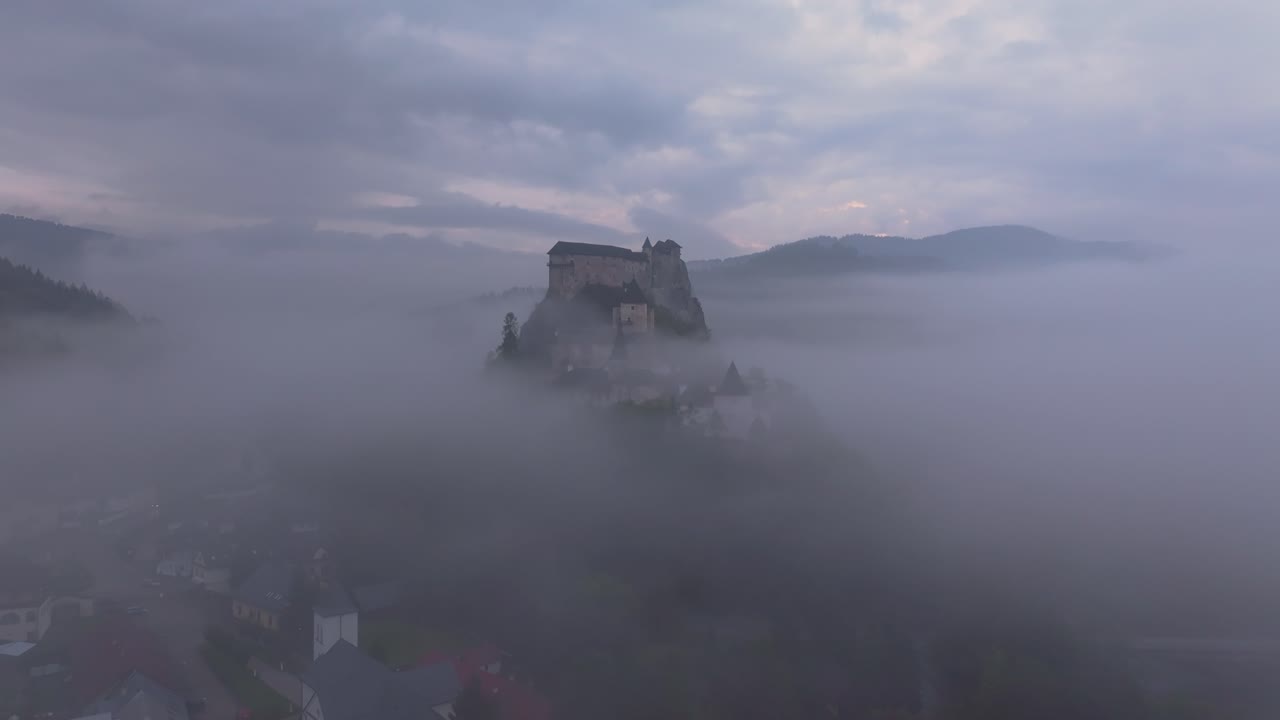 Droneoptagelse af Orava Slot, der dukker frem fra morgentågen, Slovakiet