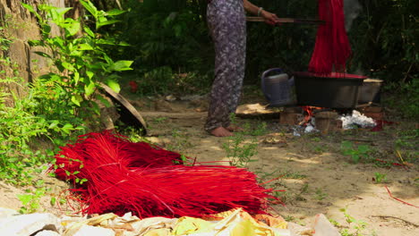 Person-putting-dyed-red-straws-on-the-floor-to-dry-in-the-sunlight