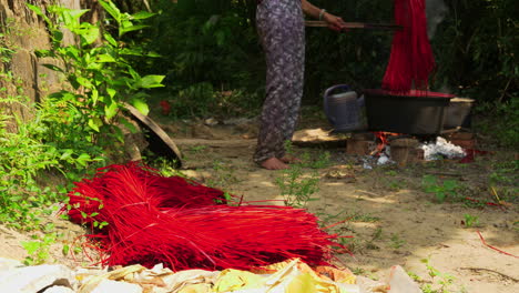 persona poniendo pajitas rojas teñidas en el suelo para que se sequen a la luz del sol
