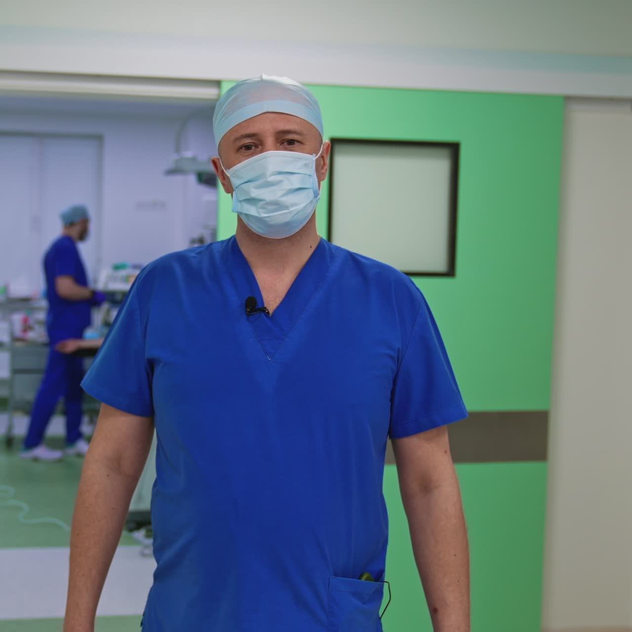 Portrait of a doctor in mask. Professional surgeon in medical uniform standing in clinic and talking on camera. Health care concept
