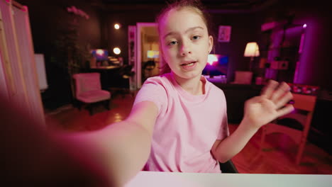 cute kid holding selfie smartphone camera, filming herself doing room tour